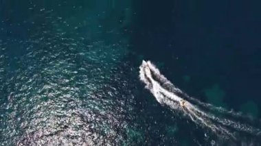 Denizde yüzen motorlu bir teknenin drone görüntüsü köpüklü bir iz bırakıyor.