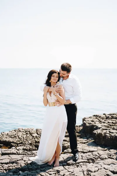 Жених и невеста обнимаются на скалистом берегу — стоковое фото
