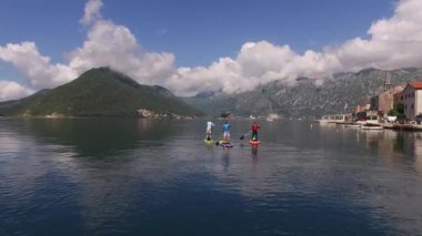 Sörfçüler Perast 'i geçip sörf tahtalarında yüzerler. Karadağ