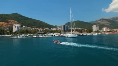 Şişme tekne Budva 'daki iskelenin yanından geçiyor demirli yatlarla.