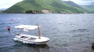 Tekne, dağların arka planında ve St. George adasında sallanıyor. Perast, Karadağ
