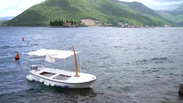 Barco balancea en las olas contra el telón de fondo de las montañas y la isla de San Jorge. Perast, Montenegro — Vídeos de Stock