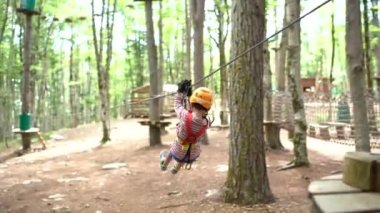 Güvenlik halatıyla ağaçlar arasında halatla gezen bir çocuk. Arka plan