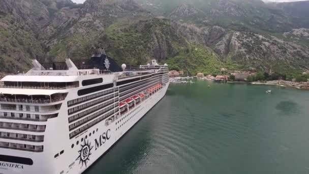 Luxe cruiseschip tegen de achtergrond van de oude stad Kotor en groene bergen. Drone aanzicht — Stockvideo