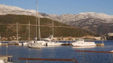 Yelkenli Budva 'daki rıhtımdan karla kaplı dağların arkasına doğru yelken açıyor.