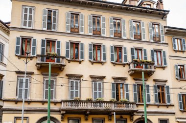 Pencerelerinde ve balkonlarında panjurlar olan eski binanın ön cephesi. Milan, İtalya