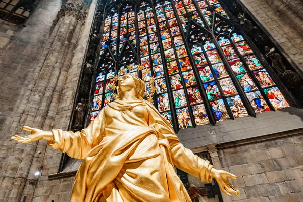 Socha Madony ve zlatě na pozadí barevného okna v Duomo. Milan, Itálie — Stock fotografie