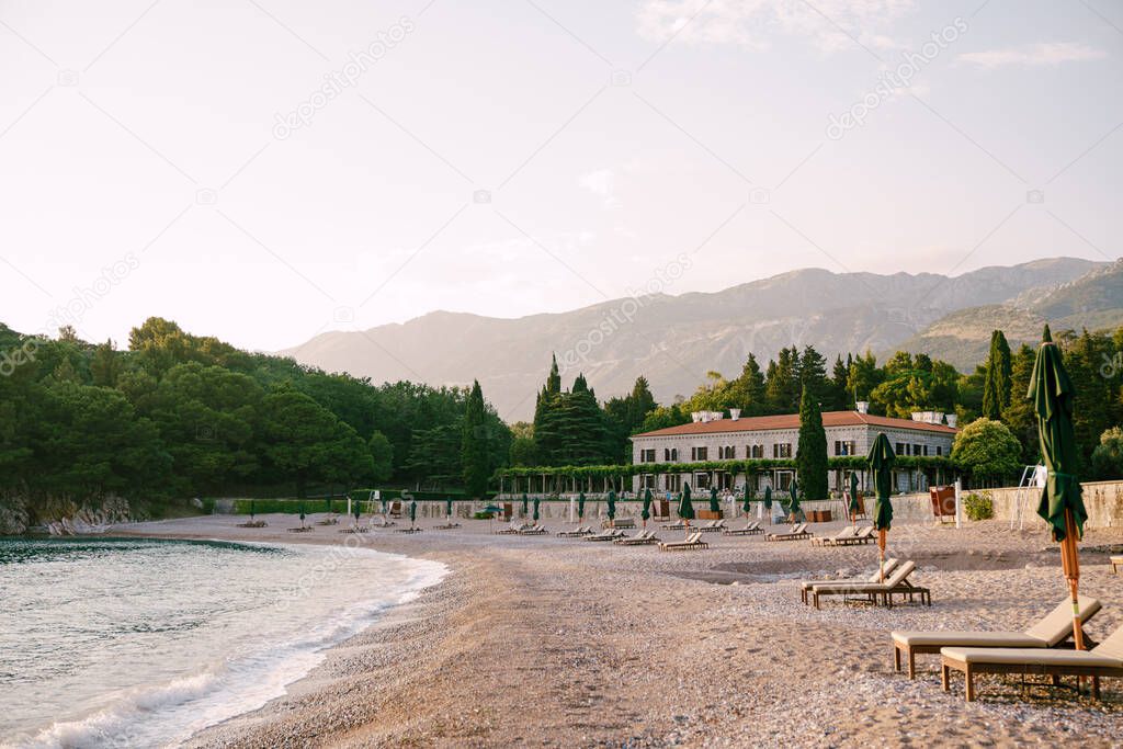 Sun loungers with mattresses and umbrellas on the beach. Villa Milocer. Montenegro