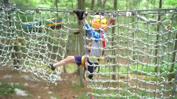 Pojke kliver över sektioner på en meshbro — Stockvideo