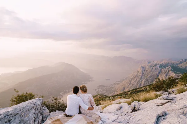 Noiva e noivo sentar na montanha e olhar para a baía — Fotografia de Stock