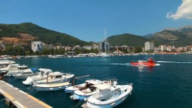 Tekneler iskelenin yanından demirli yatlarla geçer. Budva. Karadağ. Yüksek kalite 4k görüntü