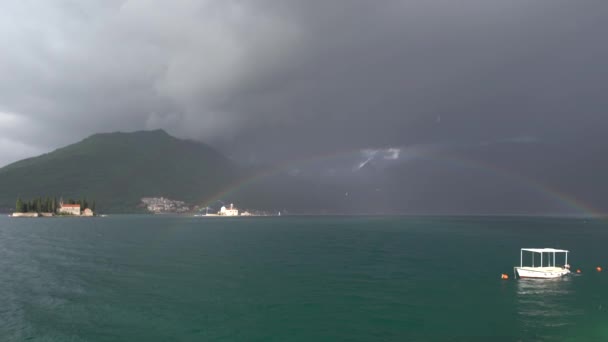 Gewitterwolken und ein Regenbogen über der Insel Gospa od Skrpjela. Perast, Montenegro — Stockvideo