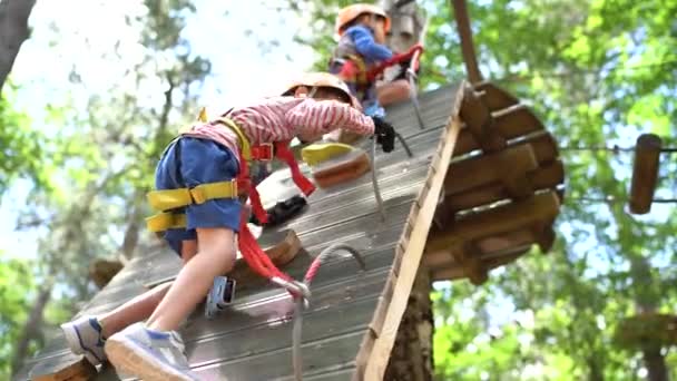 Liten pojke klättrar uppför klätterväggen genom att arrangera om karbinerna — Stockvideo