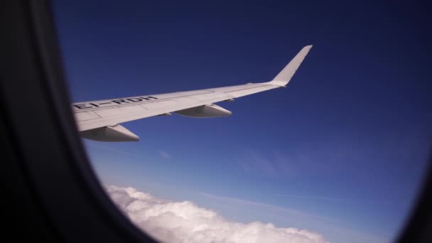 Vliegtuigvleugel vliegt in de lucht boven witte wolken door de patrijspoort — Stockvideo