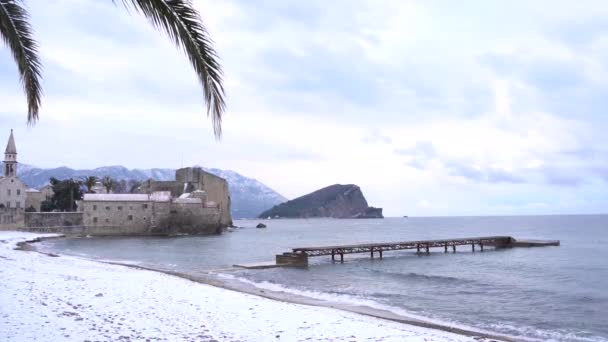 Pier bij het oude centrum van Budva op de achtergrond van een besneeuwd strand — Stockvideo