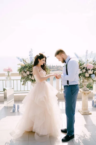 Le marié met l'anneau sur le doigt des mariées lors de la cérémonie de mariage sur le fond des décorations de mariage — Photo