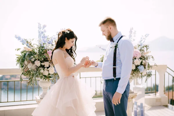Наречена кладе нареченого на палець нареченої під час весільної церемонії на тлі весільних прикрас — стокове фото