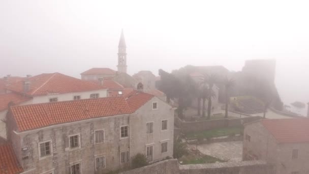 Rote Dächer der Altstadt von Budva im dichten Nebel — Stockvideo