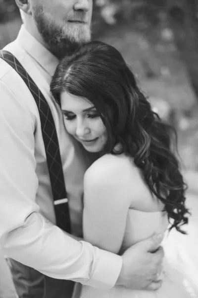 The groom gently hugs the bride, who leaned against his chest and closed her eyes, black and white — Stock Photo, Image