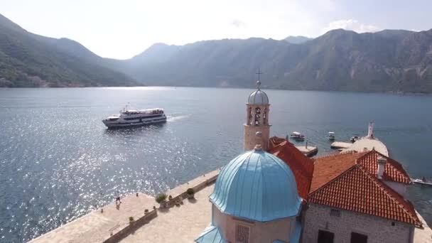 Barco turístico navega por la isla con la Iglesia de Nuestra Señora de las Rocas — Vídeos de Stock