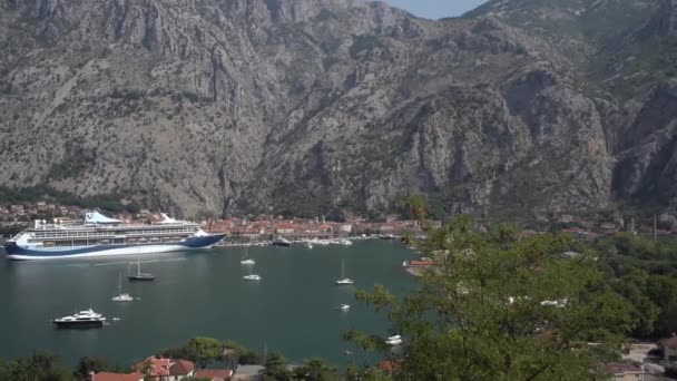 Luxe cruiseschip aangemeerd nabij de kust van de oude stad Kotor op de achtergrond van bergen — Stockvideo