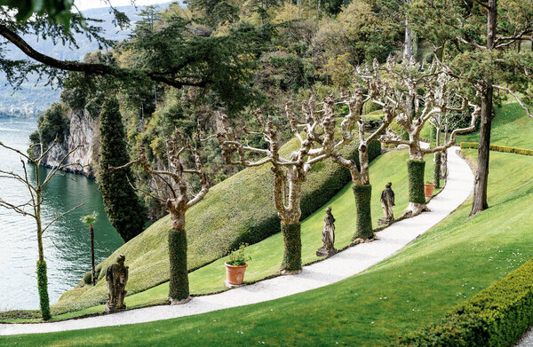 Скульптуры в плоской аллее деревьев на склоне холма Вилла Бальбианелло. Озеро Комо, Италия