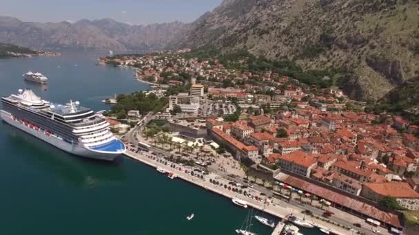 Oude stad van Kotor in de buurt van de baai met boten en een enorm cruiseschip — Stockvideo