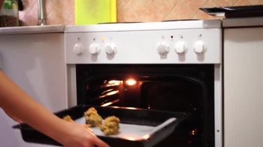 Kurabiyeleri yanan bir ampulle fırına koyuyor.