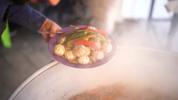 Chef tar ut vitlökshuvuden och peppar från kitteln med uzbekisk pilaf — Stockvideo