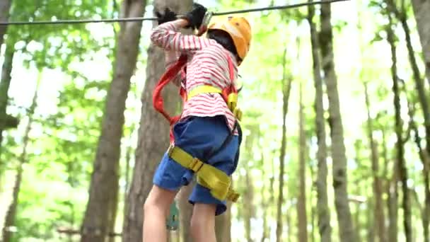 Хлопчик ходить на жорсткій мотузці, тримаючи руки на безпечній мотузці — стокове відео