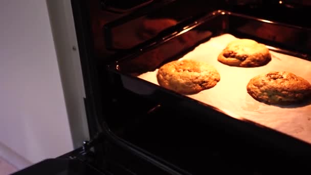 Dziewczyna wyciąga gotowe amerykańskie ciasteczko czekoladowe z piekarnika — Wideo stockowe