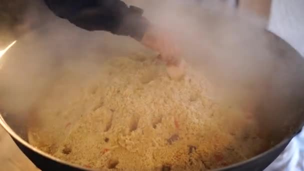 Chef fait des trous avec la poignée d'une cuillère à vapeur pour s'échapper dans le pilaf ouzbek dans un chaudron — Video