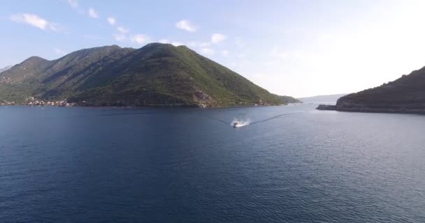 Das weiße Motorboot segelt auf dem Meer an der bergigen Küste vorbei. Perast, Montenegro — Stockvideo