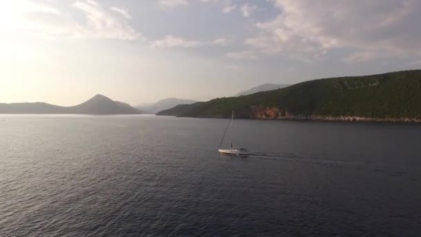 Bateau à voile navigue sur la mer le long de la côte montagneuse jusqu'à l'île de Mamula — Video