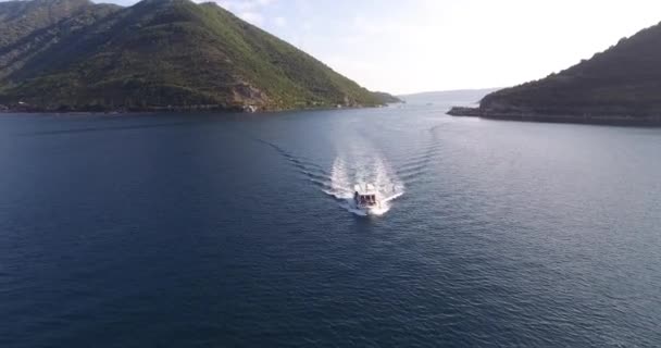 Белая моторная лодка плывет по морю мимо горного побережья — стоковое видео