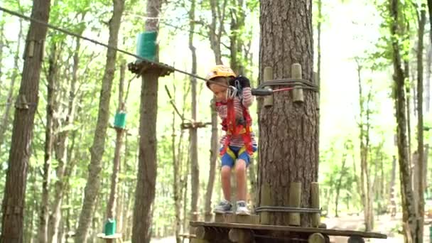 Jongen begint te bewegen op een ziplijn van een houten platform — Stockvideo
