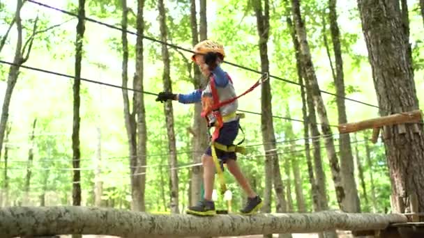 Anak laki-laki berjalan di sepanjang mistar gawang berpegangan pada kabel di sisi — Stok Video