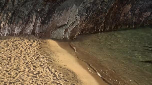 Mořské vlny se valí na písečný břeh poblíž útesu — Stock video