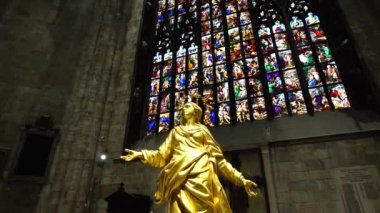 Meryem Ana 'nın altın heykeli Duomo' daki kemerli cam pencerelere karşı. İtalya, Milan