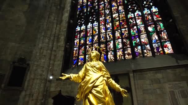 두오모에서 아치형 스테인드글라스 창문을 배경으로 한 성모 마리아의 황금 동상. 이탈리아, 밀라노 — 비디오