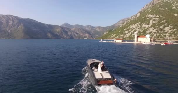 Łódź motorowa z nowożeńcami płynie po morzu na wyspę Gospa od Skrpjela — Wideo stockowe
