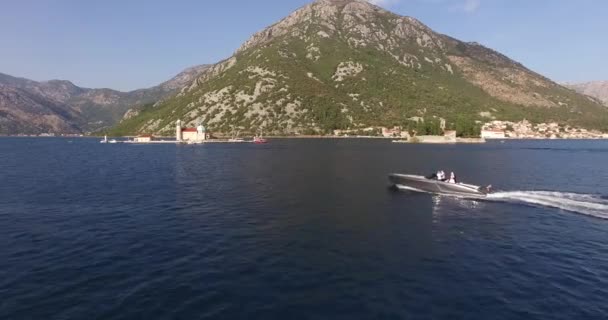 Łódź motorowa z nowożeńcami pływa po morzu na tle zielonych gór — Wideo stockowe