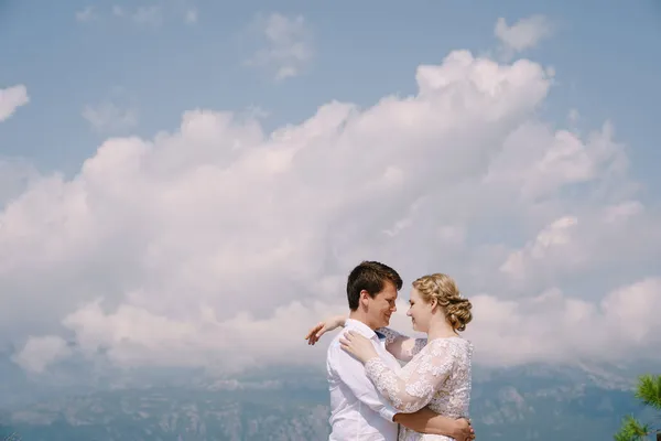 Braut und Bräutigam umarmen sich auf dem Hintergrund des Himmels — Stockfoto