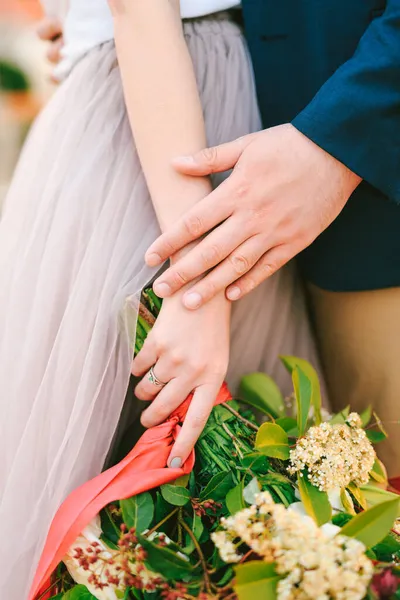 Ο άνθρωπος κρατά τις γυναίκες χέρι με ένα μπουκέτο λουλούδια στα χέρια της. Κοντινό πλάνο — Φωτογραφία Αρχείου