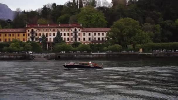 La barca a motore naviga sul Lago di Como sullo sfondo di case colorate sulla riva. Italia — Video Stock