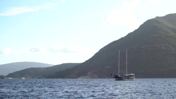 Veleiro flutua no mar contra o pano de fundo das montanhas verdes — Vídeo de Stock