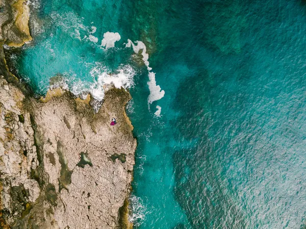 Homem e mulher abraçam-se uns aos outros nas rochas perto do mar azul. Vista superior — Fotografia de Stock