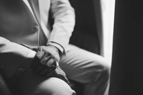 Чоловік у костюмі з кільцем на своєму маленькому пальці сидить біля вікна, крупним планом, чорно-білий — стокове фото