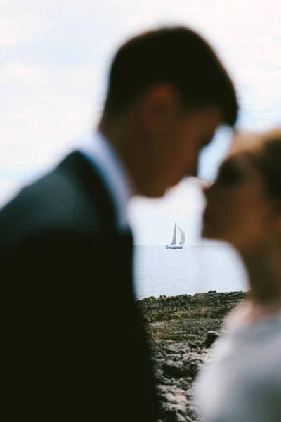 Silhouettes of almost kissing newlyweds on the background of a white sailing yacht in the open sea — Stock Photo, Image