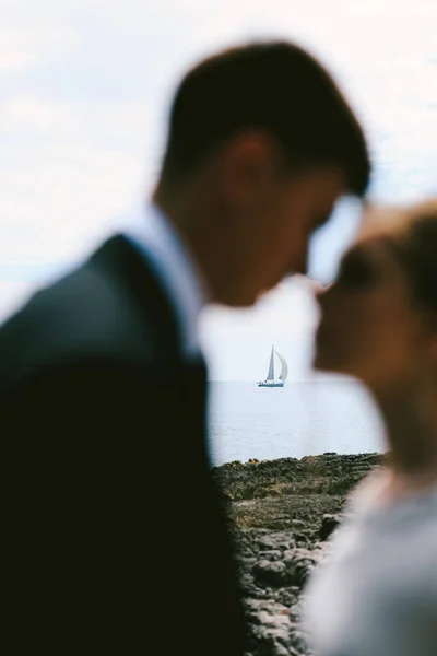 Siluetas de casi besar a los recién casados en el fondo de un yate de vela blanco en el mar abierto —  Fotos de Stock